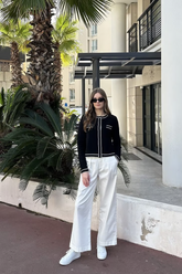 a lady in a black knit top and a pair of white pants